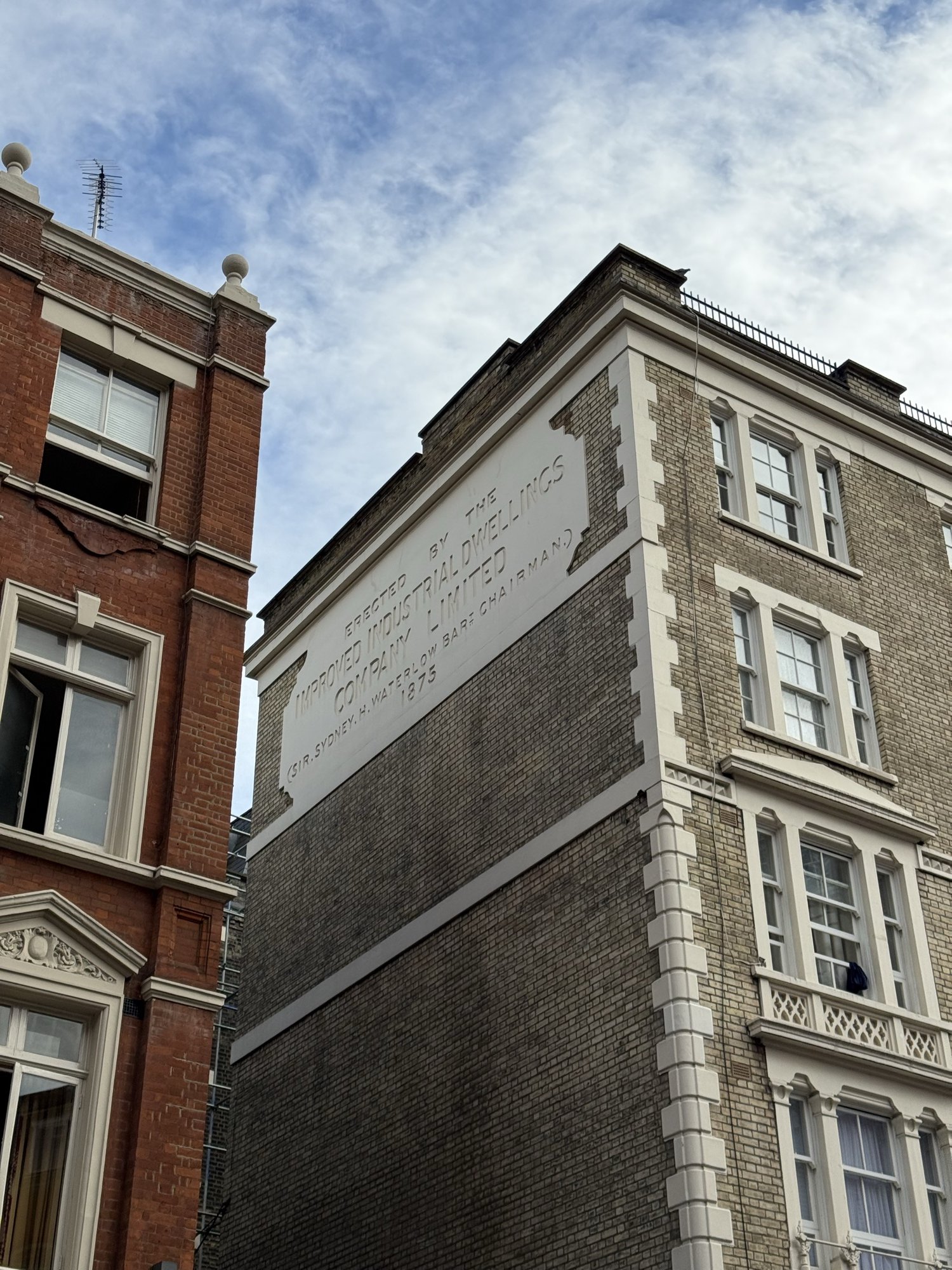 Coburg Buildings 牆上的1875年銘文，刻有改良工人住宅公司和主席悉尼・沃特洛爵士的名字。