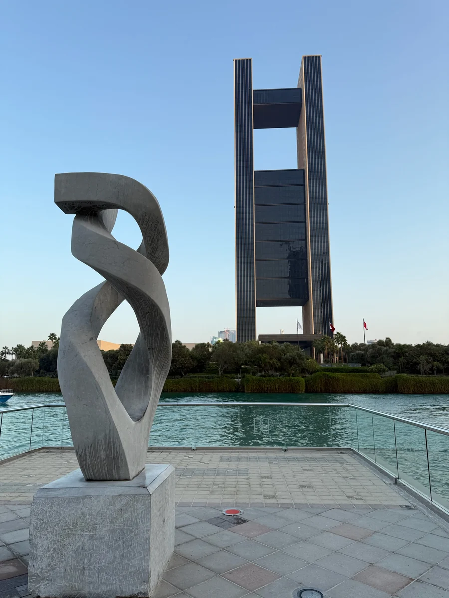 前景雕塑後方是巴林灣四季酒店，兩側高牆與橫向玻璃樓層構成門框般的輪廓。