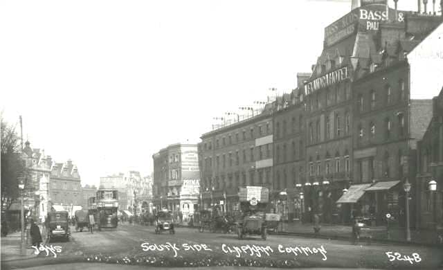 約 1910 年的 Clapham Common South Side，鏡頭朝向 Clapham High Street。來源說明指出，舊車站入口位於今天入口的道路對面；右前方帶圓頂的大樓是 Alexandra Hotel。
