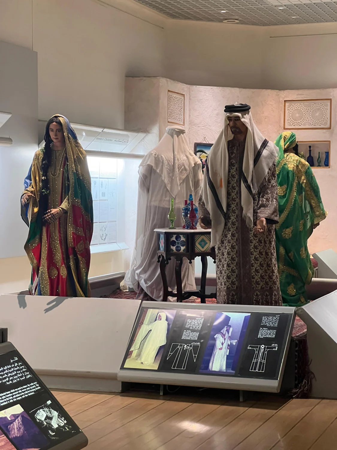 博物館內的巴林傳統衣飾展陳，攝於二〇二五年。彩色布料上飾着金色紋樣。